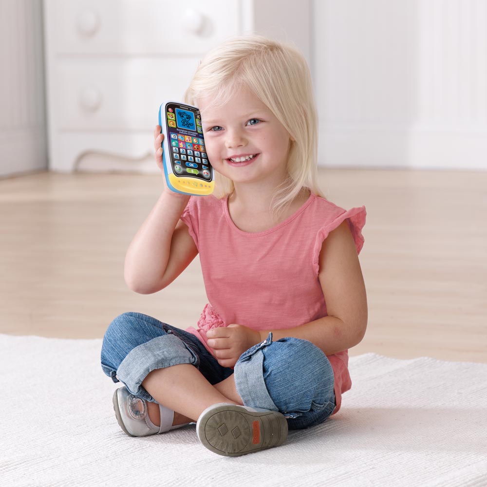 Niña de 2 años con un teléfono en la mano - jugando en casa mientras habla  por teléfono